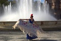 The beautiful woman dancing near the water of the fountain