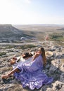 Beautiful woman with dark hair in elegant dress having picnic with fantastic view on valley with air balloons on background