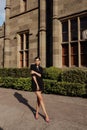 Beautiful woman with dark hair in elegant dress posing near antic castle in park