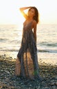 Beautiful woman with dark hair in elegant dress posing on sunset beach Royalty Free Stock Photo