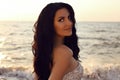 Beautiful woman with dark hair in elegant dress posing on sunset beach Royalty Free Stock Photo