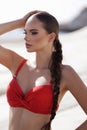 beautiful woman with dark hair in elegant red swimming suit posing in the white stones beach in Cyprus