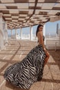 beautiful woman with dark hair in elegnt dress with zebra print posing in beach club