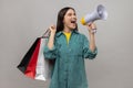 Beautiful woman with dark hair holding shopping bags and megaphone, announcing sale and discount. Royalty Free Stock Photo