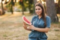 Beautiful woman in denimdress hold slice of watermelon in hands. Background of park