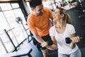 Beautiful woman doing exercises in gym with personal trainer