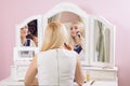 Beautiful woman is doing makeup in front of mirror. Royalty Free Stock Photo