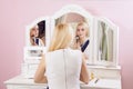 Beautiful woman is doing makeup in front of mirror. Royalty Free Stock Photo