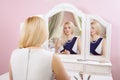 Beautiful woman is doing makeup in front of mirror. Royalty Free Stock Photo