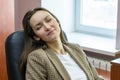 Beautiful woman dreaming with closed eyes in office chair. Royalty Free Stock Photo