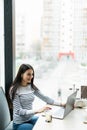 Beautiful woman dreaming about something while sitting with portable net-book in modern cafe bar. Young charming female freelancer Royalty Free Stock Photo