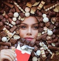 Beautiful woman dreaming while tasting eating enjoying chocolate bar on chocolate candy background Royalty Free Stock Photo