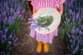 Blooming lavender field and beautiful woman with dress and bouquet of flowers in hat