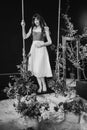 a beautiful woman in a dress stands on a swing in peony flowers. black and white Royalty Free Stock Photo