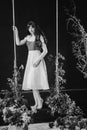 a beautiful woman in a dress stands on a swing in peony flowers. black and white Royalty Free Stock Photo