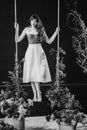 a beautiful woman in a dress stands on a swing in peony flowers. black and white Royalty Free Stock Photo