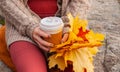 Beautiful woman drinking coffee in autumn park. Woman holding cup of coffee in the hands outdoor Royalty Free Stock Photo