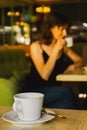 Beautiful woman drinking coffee in cafe, focus on foreground. Daily life concept. Brunette girl with cup of tea on the sofa. Royalty Free Stock Photo