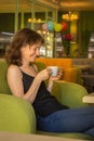Beautiful woman drinking coffee in cafe. Daily life. Enjoy your life. Brunette girl with cup of tea on the sofa. Cozy lifestyle Royalty Free Stock Photo