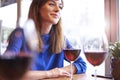 Beautiful woman drinking red wine with friends in cafe, portrait with wine glass near window. Vocation holidays evening bar conce Royalty Free Stock Photo