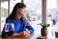 Beautiful woman drinking red wine with friends in restaurant, portrait with wine glass near window. Vocation holidays bar concept Royalty Free Stock Photo