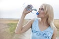 Beautiful woman drinking water from bottle while standing on field Royalty Free Stock Photo