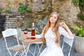 Beautiful woman drinking wine in outdoors cafe. Portrait of young blonde beauty in the vineyards having fun, enjoying a Royalty Free Stock Photo