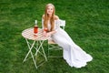 Beautiful woman drinking wine in outdoors cafe. Portrait of young blonde beauty in the vineyards having fun, enjoying a Royalty Free Stock Photo