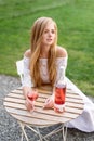 Beautiful woman drinking wine in outdoors cafe. Portrait of young blonde beauty in the vineyards having fun, enjoying a Royalty Free Stock Photo