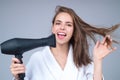 Beautiful woman drying her hair with a hairdryer isolated on studio background. Young woman with blow dryer drying hair Royalty Free Stock Photo