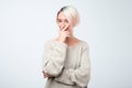 Beautiful woman with dyed short hair looking holding hand under chin intending to realize tricky plan. Royalty Free Stock Photo