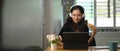 A beautiful woman is eating a croissant while using a computer tablet. Royalty Free Stock Photo