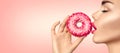 Beautiful woman eating pink donut