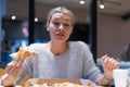 Beautiful woman eating pizza and drinking cola while sitting inside expres restaurant late at night Royalty Free Stock Photo