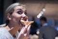 Beautiful woman eating pizza and drinking cola while sitting inside expres restaurant late at night Royalty Free Stock Photo