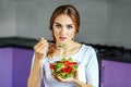 A beautiful woman eats a delicious vegetable salad. The concept Royalty Free Stock Photo