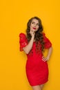 Beautiful woman in elegant red lace dress is holding hand on chin, looking up and thinking Royalty Free Stock Photo