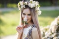 Young beautiful woman with a pleasant smile in  alone in a wreath of fresh flowers walks in a spring flowering park Royalty Free Stock Photo