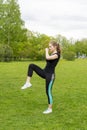 Beautiful woman is engaged in martial arts in the park on nature. Legs warm up