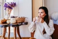 beautiful woman enjoying a cup of coffee during healthy breakfast at home. Writing on notebook. Adorable golden retriever dog Royalty Free Stock Photo