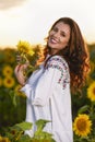 Beautiful woman enjoying nature in the sunflower field at sunset. Traditional clothes. Attractive brunette woman with long and Royalty Free Stock Photo