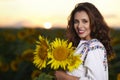 Beautiful woman enjoying nature in the sunflower field at sunset. Traditional clothes. Attractive brunette woman with long and Royalty Free Stock Photo