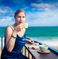 Beautiful woman enjoying tea on cafe terrace at seaside Royalty Free Stock Photo