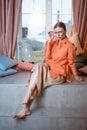 woman in the studio sits on background of window in glasses and bright clothes Royalty Free Stock Photo