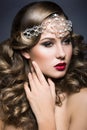 Beautiful woman with evening make-up and curls and big jewelry on her head. Beauty face. Royalty Free Stock Photo