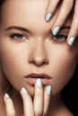 Beautiful woman face with blue nails manicure, clean skin