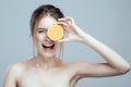 Beautiful woman face with juicy orange on grey background. Natural beauty and spa. Royalty Free Stock Photo