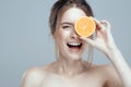 Beautiful woman face with juicy orange on grey background. Natural beauty and spa. Royalty Free Stock Photo
