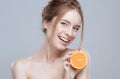 Beautiful woman face with juicy orange on grey background. Natural beauty and spa. Royalty Free Stock Photo