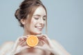 Beautiful woman face with juicy orange on grey background. Natural beauty and spa. Royalty Free Stock Photo